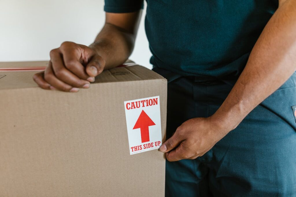 A mover carefully handling a box labeled “Caution: This Side Up”